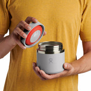 Person opening a sage green Hydro Flask food jar against a white background. 