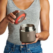 Person opening a brown Hydro Flask food jar against a white background. 