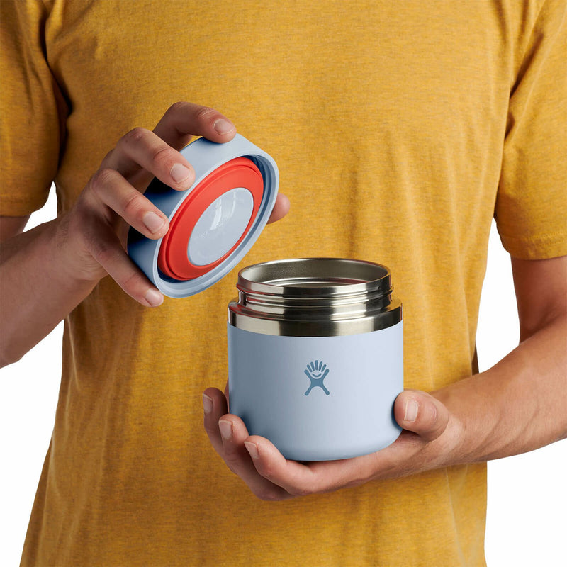 Person opening a light blue Hydro Flask food jar against a white background. 