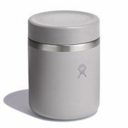 A light gray insulated can cooler with a matching lid and a stainless steel band, featuring the Hydro Flask logo on the front, set against a plain white background.