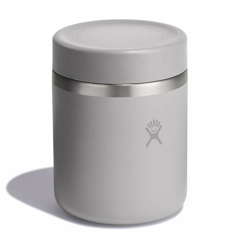 A light gray insulated can cooler with a matching lid and a stainless steel band, featuring the Hydro Flask logo on the front, set against a plain white background.