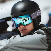 Person wearing a black helmet and goggles with a blurred background