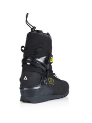 Back view of a black ski boot with yellow accents against a white background. 