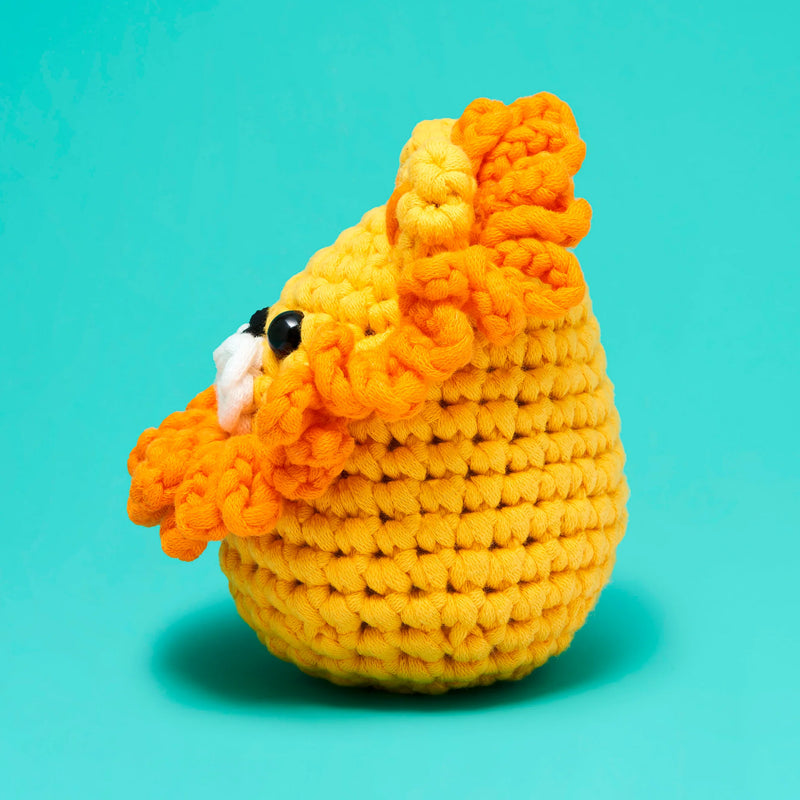 Crocheted yellow and orange lion toy on a teal background
