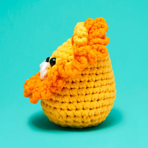 Crocheted yellow and orange lion toy on a teal background