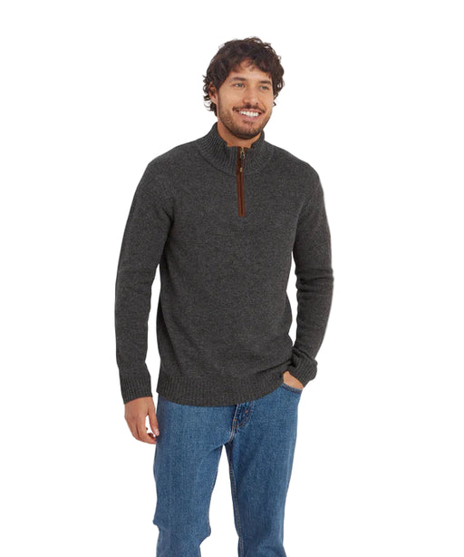 Man wearing a dark gray half-zip sweater and blue jeans on a white background