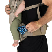 Person using a baby carrier with a baby wearing green pants and a blue blanket.