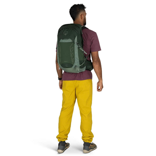 Person wearing a green backpack and yellow pants on a white background