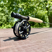 The reel of a fishing rod sitting on a wood table