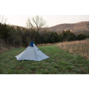 White tent with blue tip in a field.