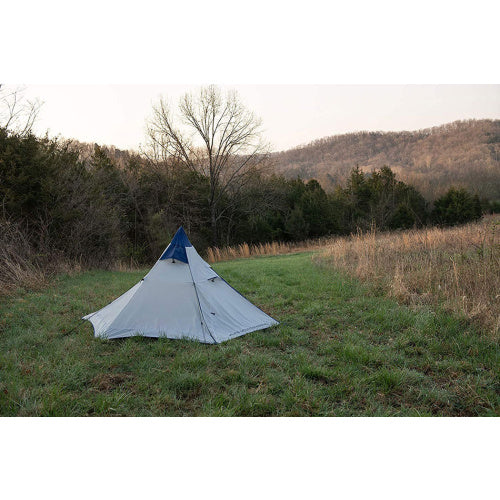 White tent with blue tip in a field.