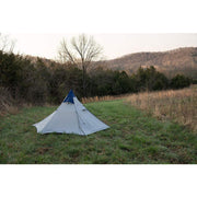 White tent with blue tip in a field.