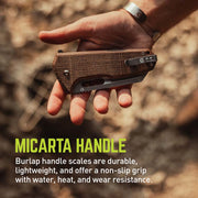 Hand holding a knife with a Micarta handle against a blurred natural background