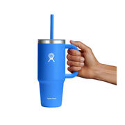 A blue Hydro Flask handled tumbler with a matching blue straw and silver rim, held by a hand against a plain white background.