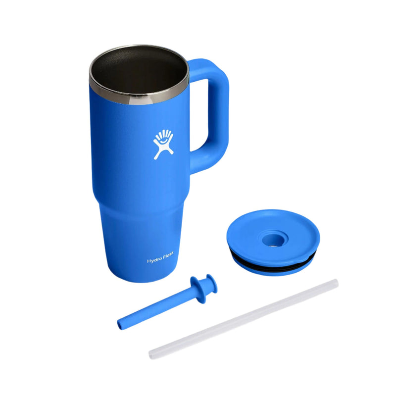 A blue Hydro Flask travel tumbler with a handle, shown with its lid, straw, and straw insert on a clean white background.