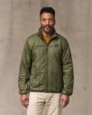 Man wearing a green jacket against a gray background