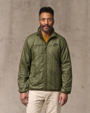 Man wearing a green jacket against a gray background