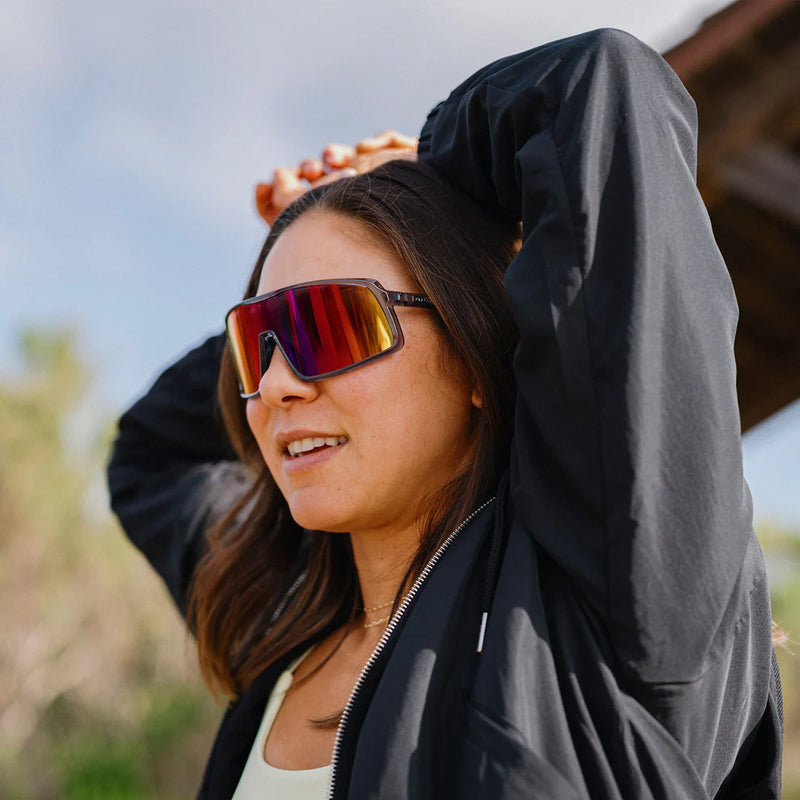 A person wearing gray glasses with multicolored lenses outside