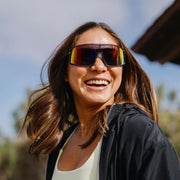 A person wearing gray glasses with multicolored lenses outside