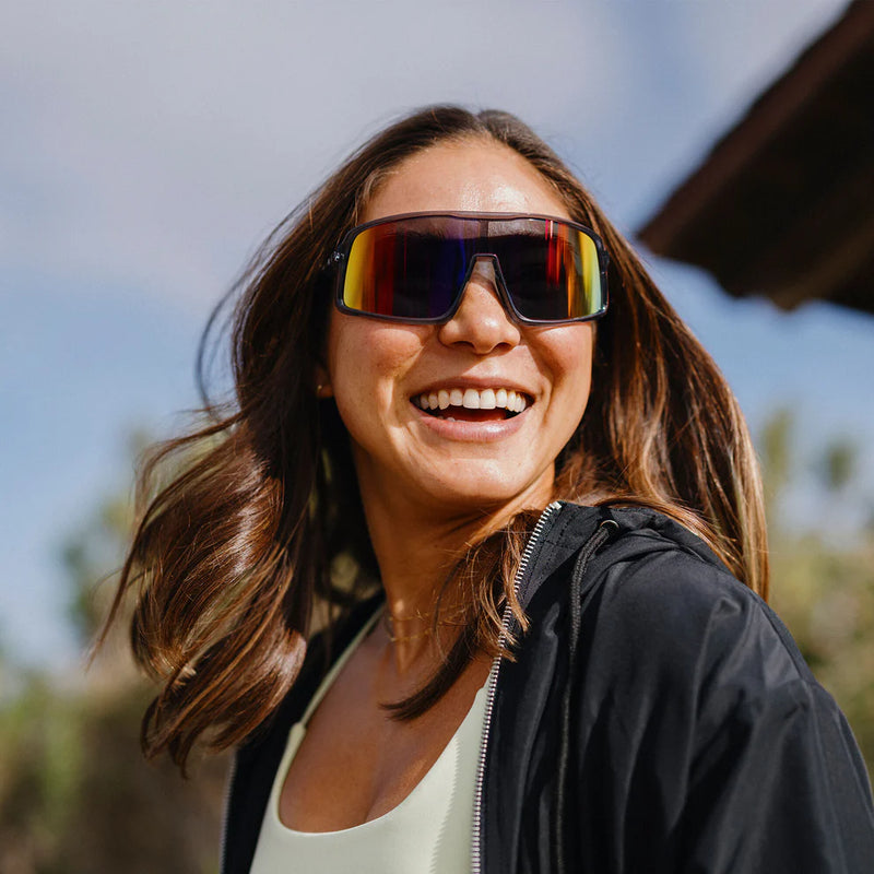 A person wearing gray glasses with multicolored lenses outside