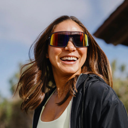 A person wearing gray glasses with multicolored lenses outside