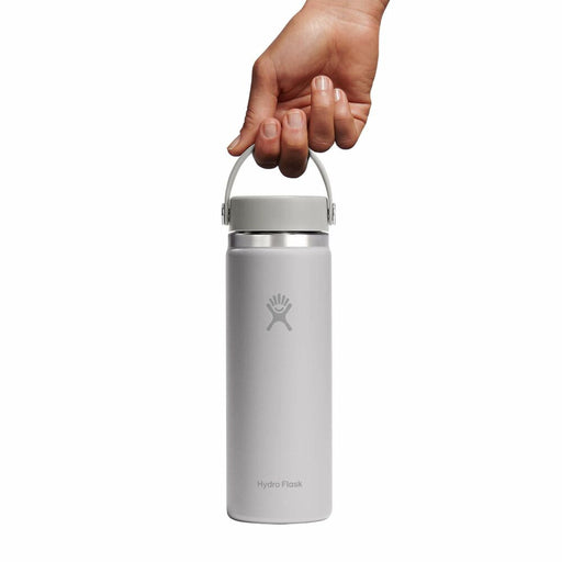Hand holding a silver Hydro Flask water bottle on a white background