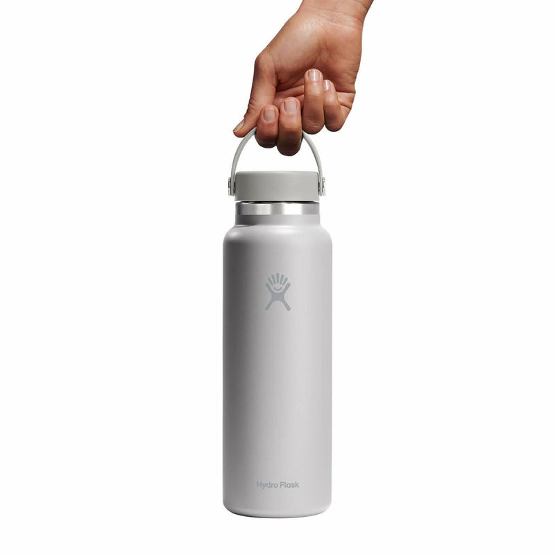 Hand holding a silver Hydro Flask water bottle on a white background