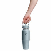 Light blue water bottle with a handle held by a hand on a white background